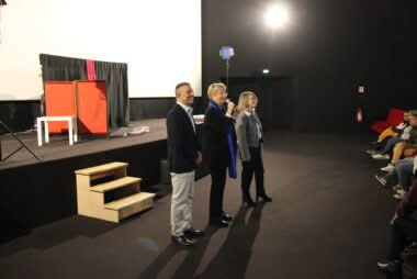trois personnes au micro qui s'adressent à une salle de spectacle